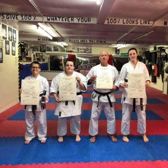 Sensei Dave Fraser and Ken Shu Dojo karate students holding their black belt grading certificates