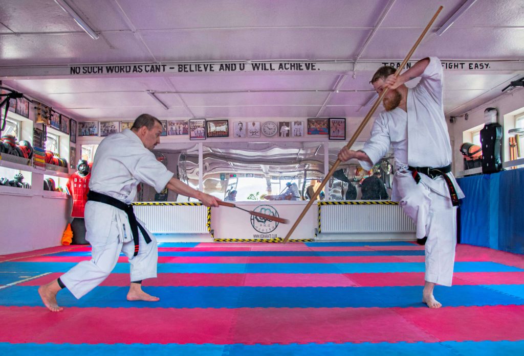 Two male karate students sparring with weapons