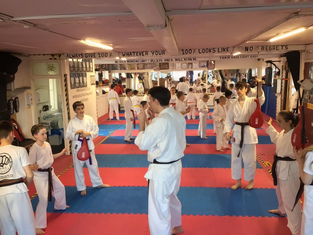 Young KSD karate students being taught speed and reaction drills on paddles