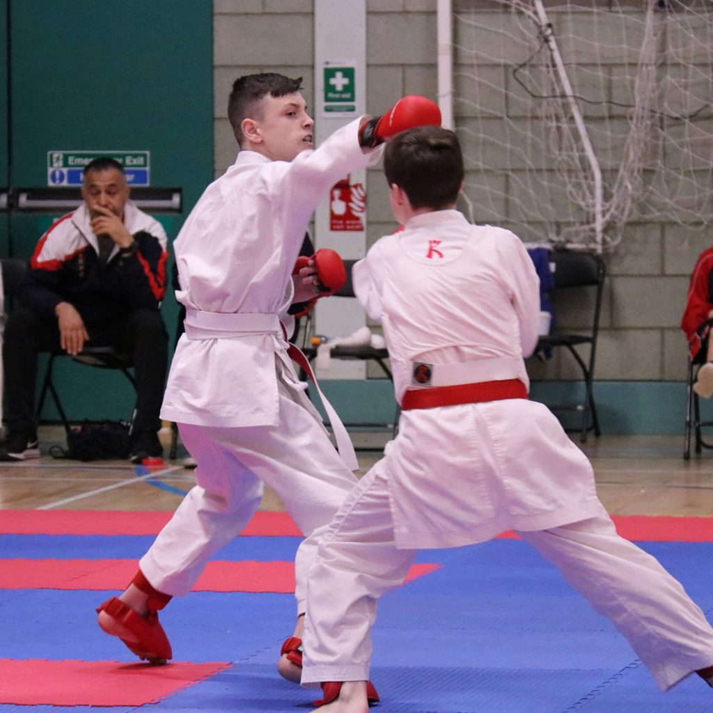 Young male karate kumite fighter throwing punch
