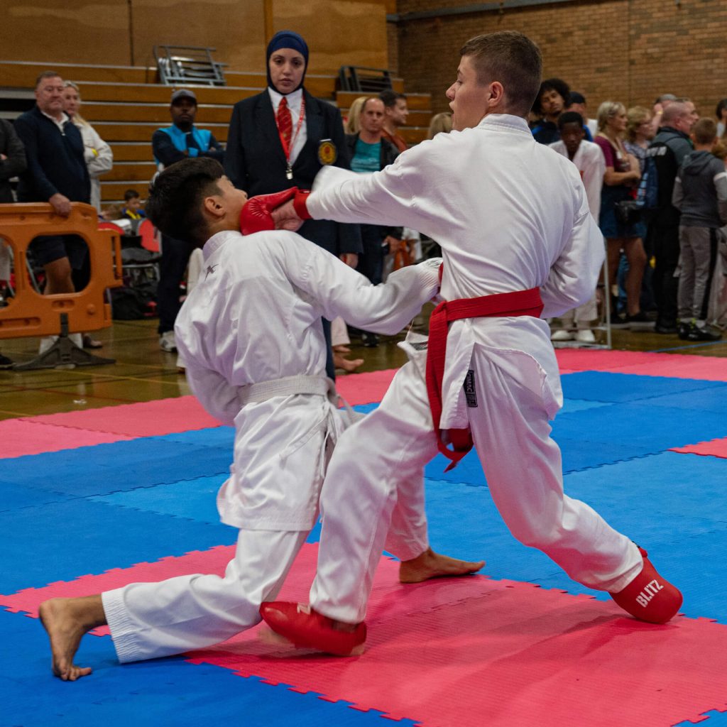 Young male karate kumite fighter throwing punch